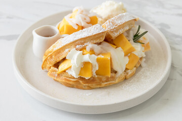 Delicious waffle mango dessert with young coconut and whipped cream.
