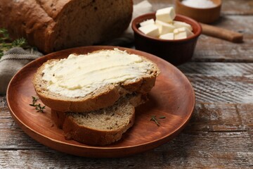 Fresh bread with butter on wooden table, closeup