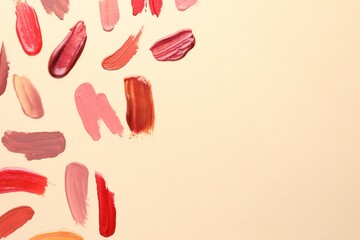 Samples of different lip products on beige background, top view. Space for text