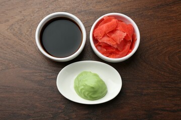 Hot wasabi paste, soy sauce and ginger on wooden table, flat lay