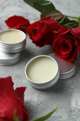 Natural solid perfume in containers and roses on grey table