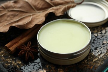 Natural solid perfume in container, spices and dry leaf on surface, closeup