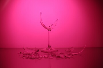Pieces of broken wine glass against deep pink background, color tone effect