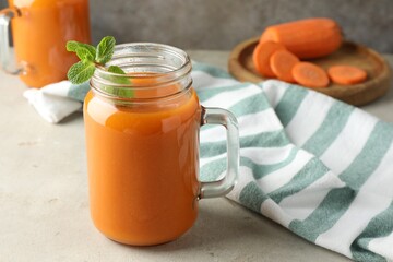 Fresh carrot juice and mint in mason jar on gray textured table