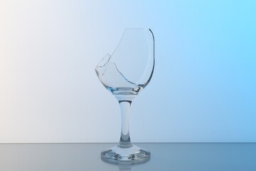 Broken wine glass on table against light blue gradient background