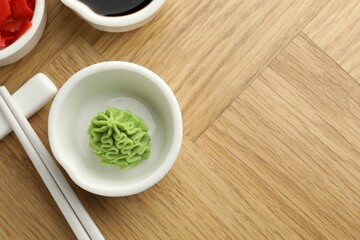 Hot wasabi paste, soy sauce, ginger and chopsticks on wooden table, flat lay. Space for text