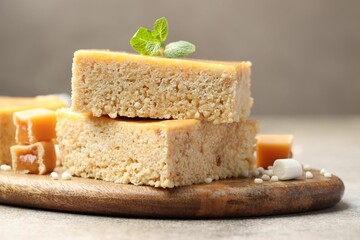 Delicious puffed rice bars, candies and mint on gray textured table, closeup