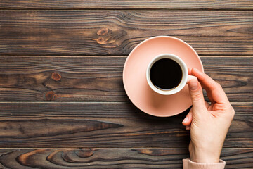 Minimalistic style woman hand holding a cup of coffee on Colored background. Flat lay, top view espresso cup. Empty place for text, copy space. Coffee addiction. Top view, flat lay