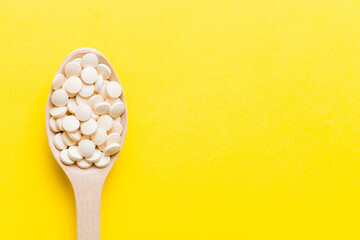 Heap of white pills on colored background. Tablets scattered on a table. Pile of red soft gelatin capsule. Vitamins and dietary supplements concept