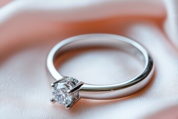 Close-up of a solitaire diamond ring on pink silk.