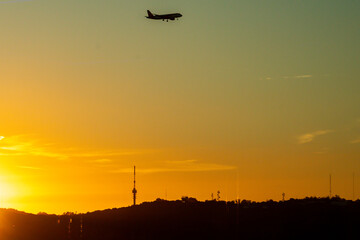 Lisbon, Portugal - Silhouette of a commercial airplane landing at sunset  with the hills of the Parque Florestal de Monsanto in the foreground