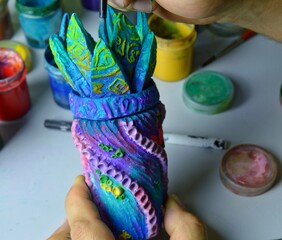 decorating a ceramic mug vessel with the hands of a master at a work table. photo without a face. the workspace of the master of pottery and ceramics is modern art and handmade art workshop. High