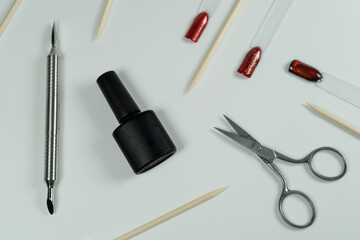 Manicure tools on a white background, including gel polish, scissors, and red gel.