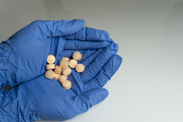 Hands in rubber gloves holding vitamins in their palms, emphasizing medical care and safety.