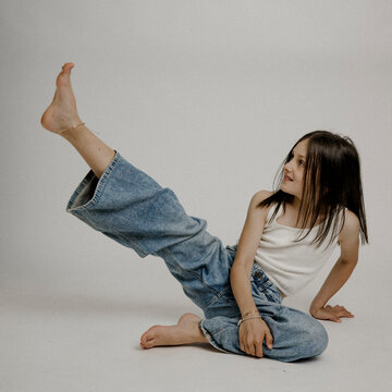 Dunkelhaariges M&auml;dchen, 10, in Blue Jeans, turnt am Boden