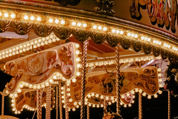 Cheshire, United Kingdom, 2024: Close up of carrousel ride at fair, red tint, vintage look, with glowy light bulbs.