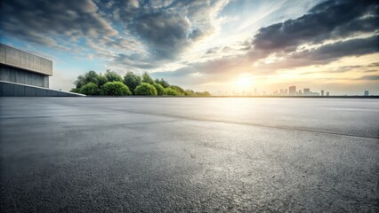 Empty asphalt road leading towards a city skyline at sunset, with a cloudy sky and a few trees in the foreground.