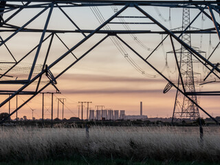 Power station framed through base of electricity pylon