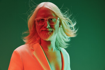 Portrait of a smiling man with long blond hair and glasses, set against a vibrant green background,...