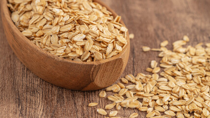 Rolled oats in a wooden bowl on a rustic wooden table. Ideal for healthy food and natural lifestyle...