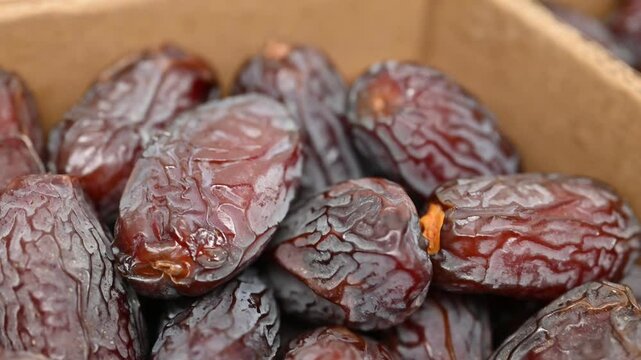 Close-Up of Fresh Dates in Cardboard Boxes. Neatly arranged fresh, ripe dates in a sectioned cardboard box, highlighting healthy, natural dried fruit ready for consumption.

