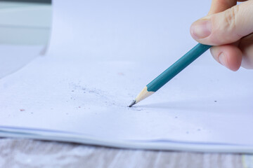 female hand writing with colored pencil on white sheet of paper