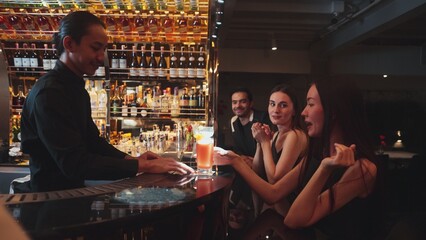 Couple talking at sitting bar with Margarita cocktail savoring sour tasty drink in happiness moment meeting while woman waiting friends at front view at luxurious counter vibrant nightclub. Vinosity.
