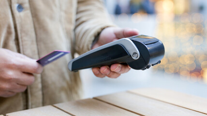 Customer paying with contactless credit card using nfc technology on pos terminal