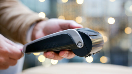 Cashier holding a contactless payment terminal accepting a credit card