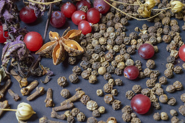 various spices scattered on a dark background with bunches of grass, laurel leaves, berries and other spices for cooking fragrant Eastern and Midwestern food. High quality photo