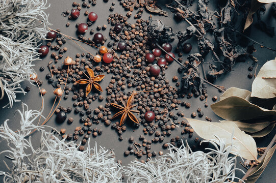 various spices scattered on a dark background with bunches of grass, laurel leaves, berries and other spices for cooking fragrant Eastern and Midwestern food. High quality photo