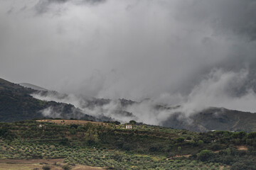 A view of the Andalusian countryside, on a rare weather day. Low clouds drifts over the landscape, with a single Finca visible amounst the Olive groves