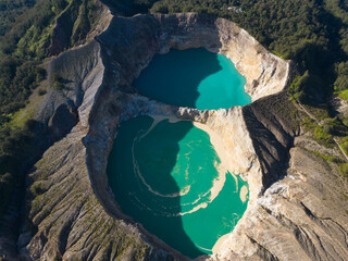 Aerial view of vibrant turquoise crater lakes surrounded by lush terrain.