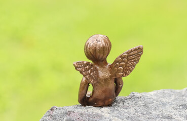 Small angel statue on a tombstone. Simple decoration angel has been brought to the graveside to comfort the grieving relatives. Empty space for text. 