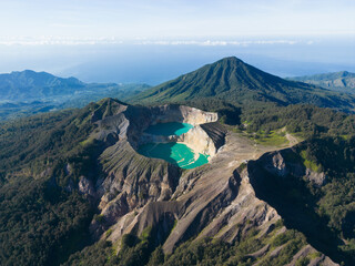 A breathtaking aerial view of a volcanic crater with turquoise lakes surrounded by lush mountains.