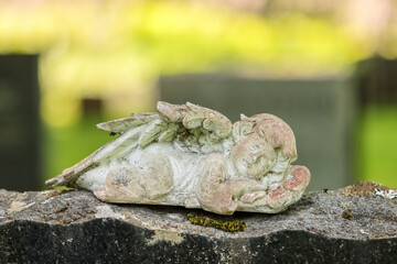Small angel statue on a tombstone. Simple decoration angel has been brought to the graveside to comfort the grieving relatives. Empty space for text. 