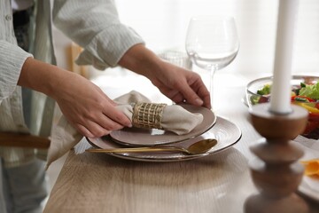 Woman setting table for dinner at home, closeup