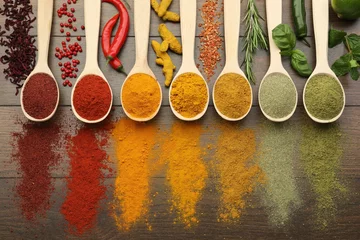 Tableau sur plexiglas Cuisine Different aromatic spices and herbs on wooden table, flat lay  © New Africa