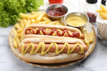 Tasty hot dogs with fries served on white marble table, closeup