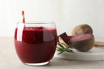 Fresh beetroot smoothie in glass on grey textured table, closeup