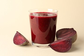 Fresh beetroot smoothie in glass and cut vegetable on beige background, closeup