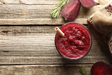 Fresh beetroot smoothie in glass, rosemary and cut vegetable on wooden table, flat lay. Space for...