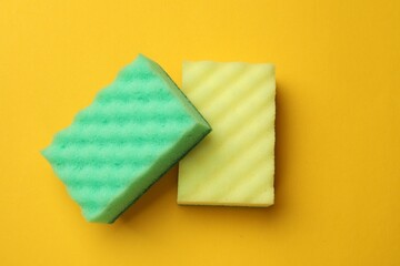 Soft sponges on yellow background, top view. Cleaning tool