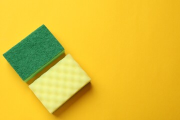 Soft sponges on yellow background, top view with space for text. Cleaning tool