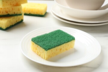 Yellow sponges and dishware on white table, closeup