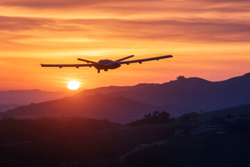 Airplane flying over scenic sunset landscape with majestic mountain silhouette