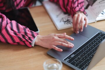Close-up of a person creating an abstract artwork on a digital tablet using a stylus, with a comic book and a glass of water visible on a wooden table nearby