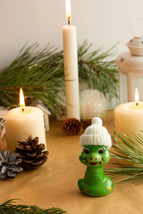 Cute candle holder in the shape of a snake surrounded by Christmas decorations. DIY. Molding from salt dough. Ecological toy. Candle for New Year's table.
