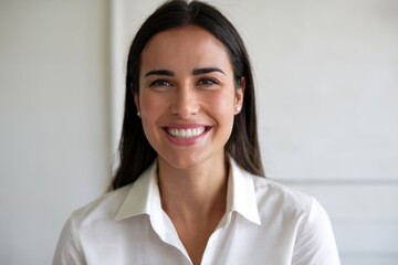 Retrato de una mujer morena de pelo largo mirando a cámara sonriente con una dentadura perfecta. Generado con IA
