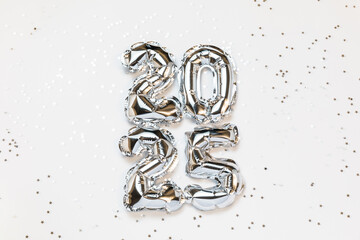 New year 2025 balloon celebration card. Silver foil helium balloon number 2025, party decoration, silver confetti stars on white background. Flat lay, merry christmas, happy holidays concept.
